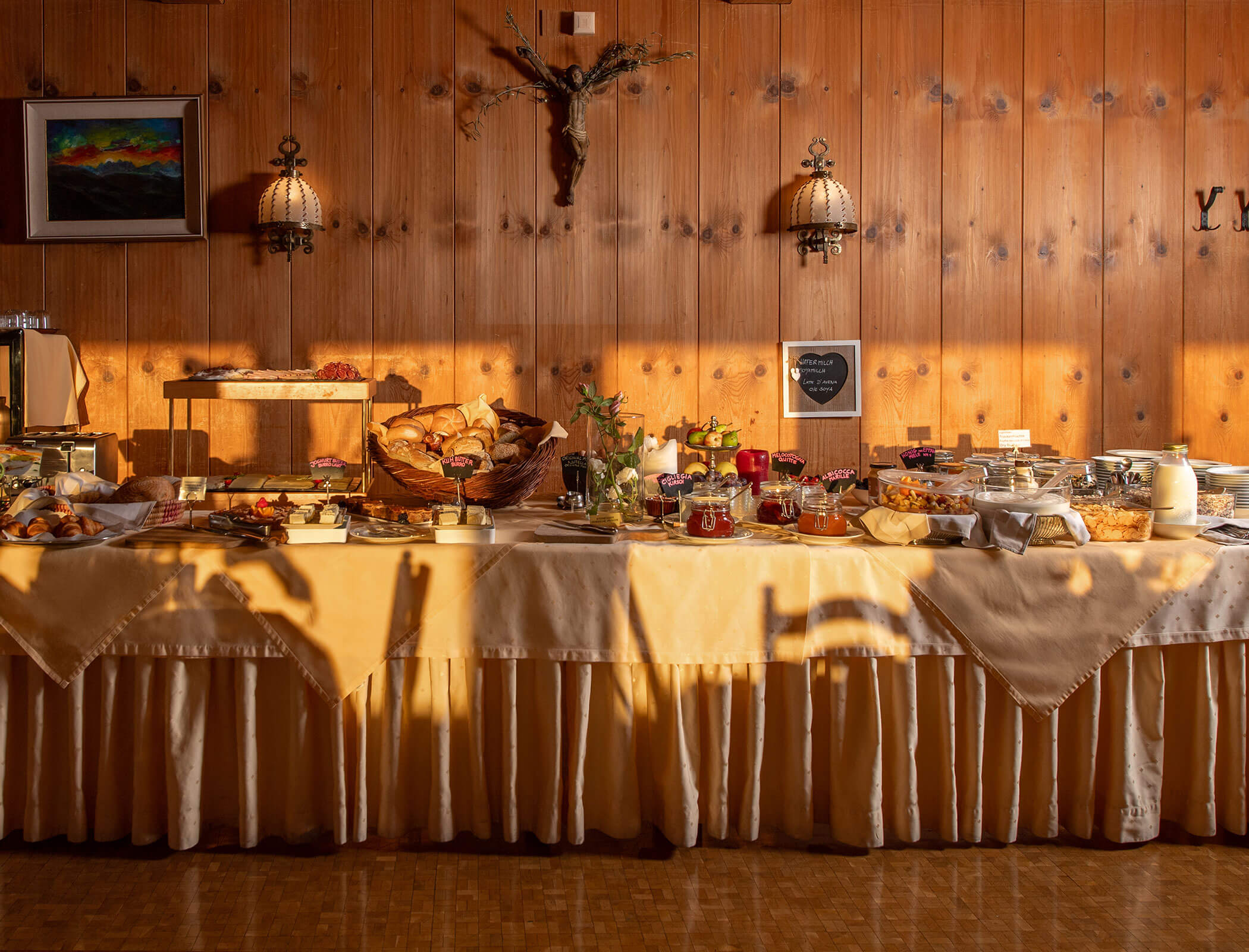Tavolo da buffet con vari cibi in una stanza caldamente illuminata con pareti in legno e arredamento rustico. - Wandergasthof Steinegger