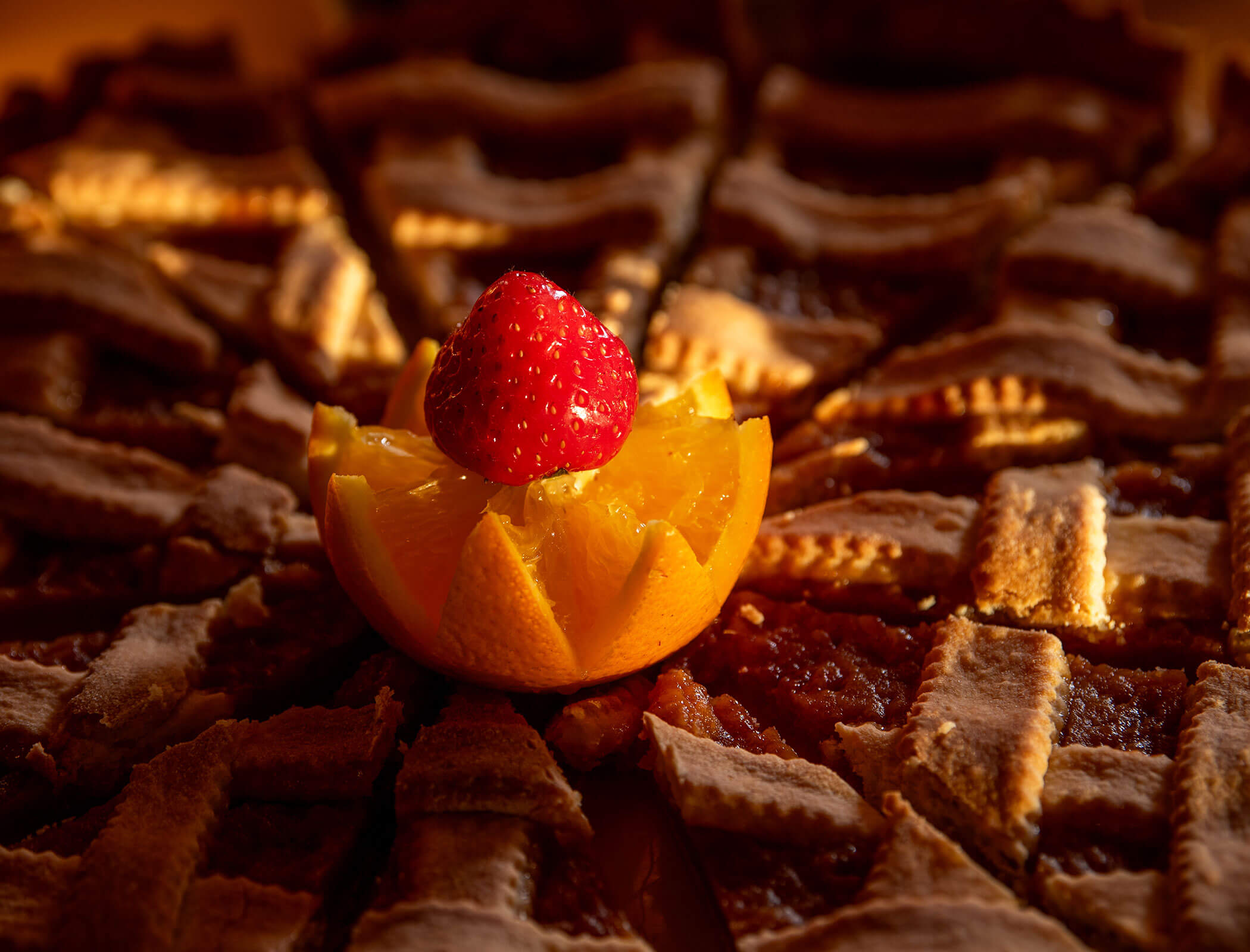 Una torta a fette sormontata da una fetta d'arancia e da una fragola intera al centro. - Wandergasthof Steinegger