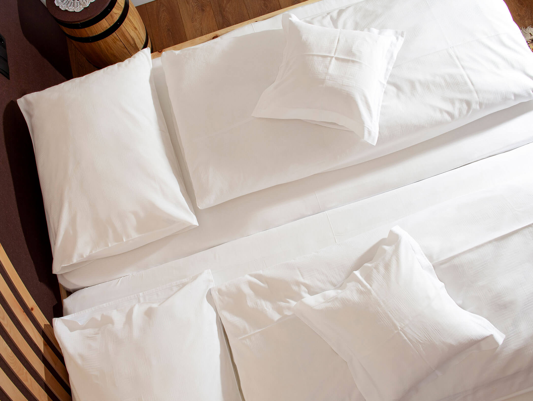 Overhead view of a neatly made bed with four white pillows and white bed linens. - Wandergasthof Steinegger
